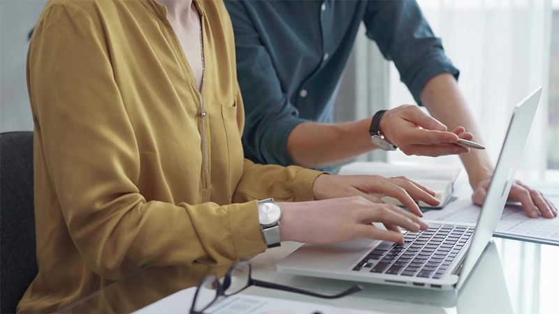 Dłonie osób pracujących przy laptopie